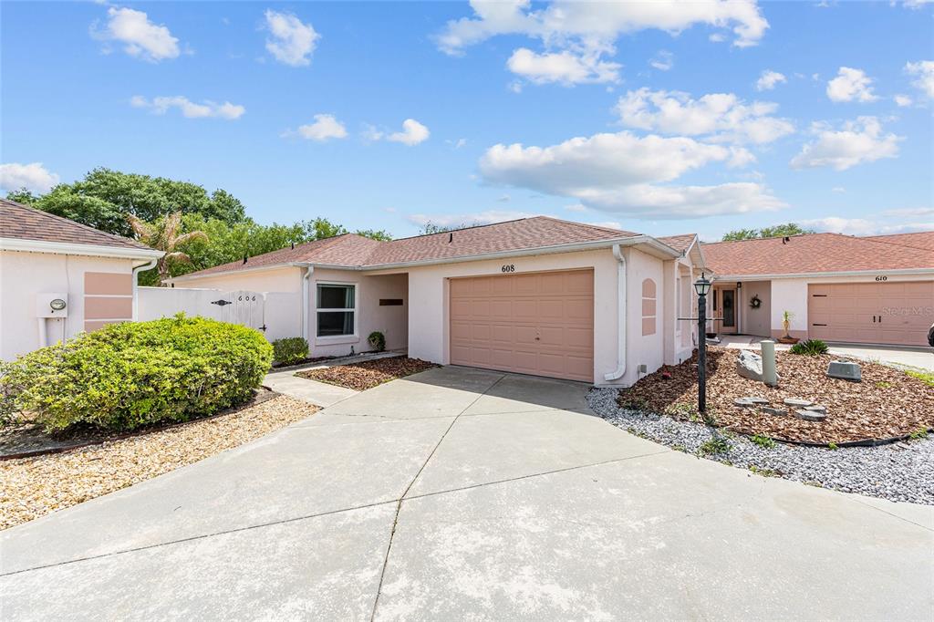 A single-story house with a tan garage, a concrete driveway, and a landscaped front yard — 608 DELGADO AVENUE, THE VILLAGES, FL