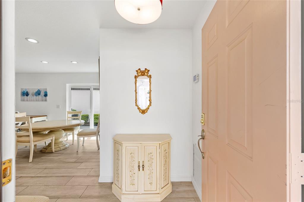 A foyer with a light-colored cabinet, a gold-framed mirror, and a view into the dining room — 608 DELGADO AVENUE, THE VILLAGES, FL