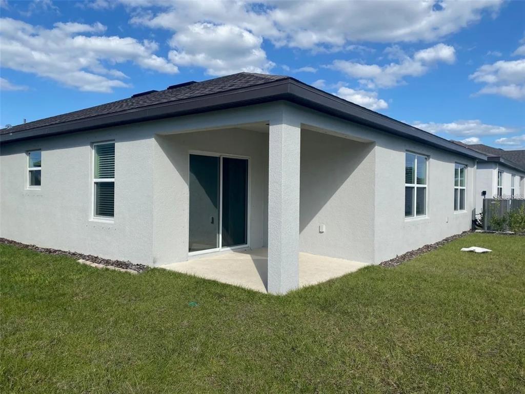 The exterior rear view of a house shows a covered patio and sliding glass doors — 9643 SUMMERS CAY CIRCLE, THONOTOSASSA, FL