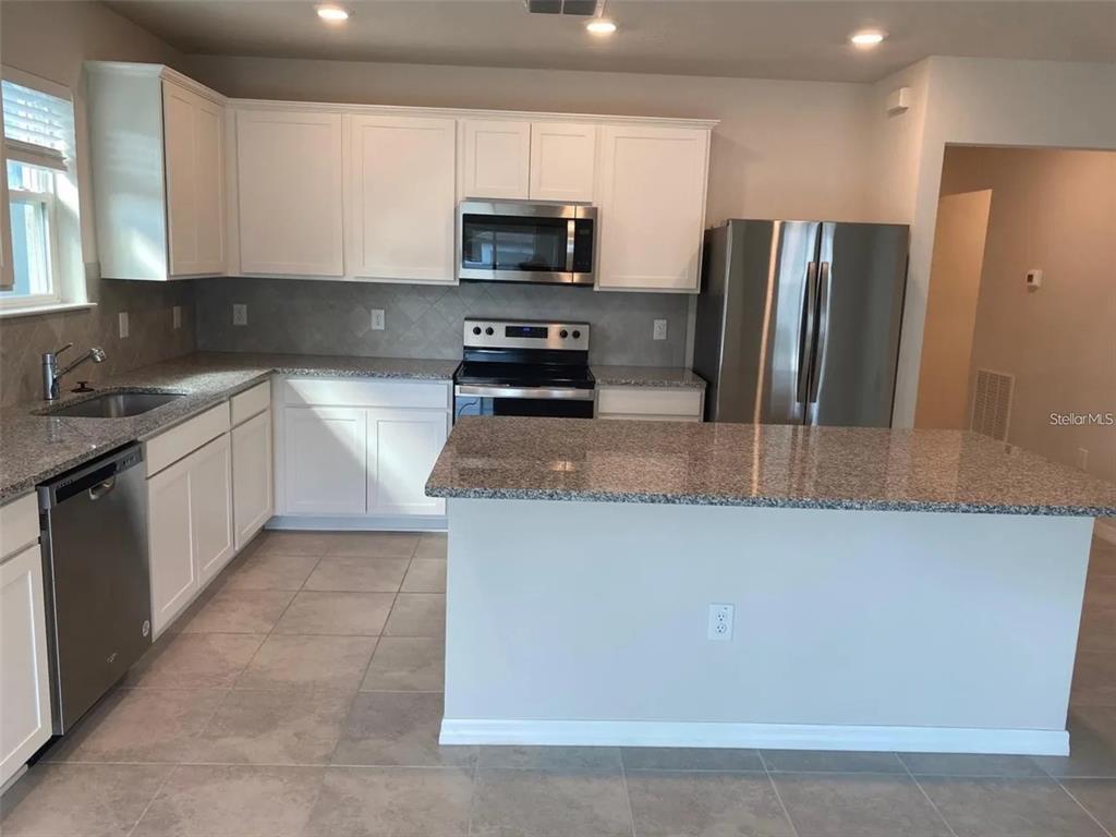 A kitchen with white cabinets, granite countertops, stainless steel appliances, and a central island — 9643 SUMMERS CAY CIRCLE, THONOTOSASSA, FL