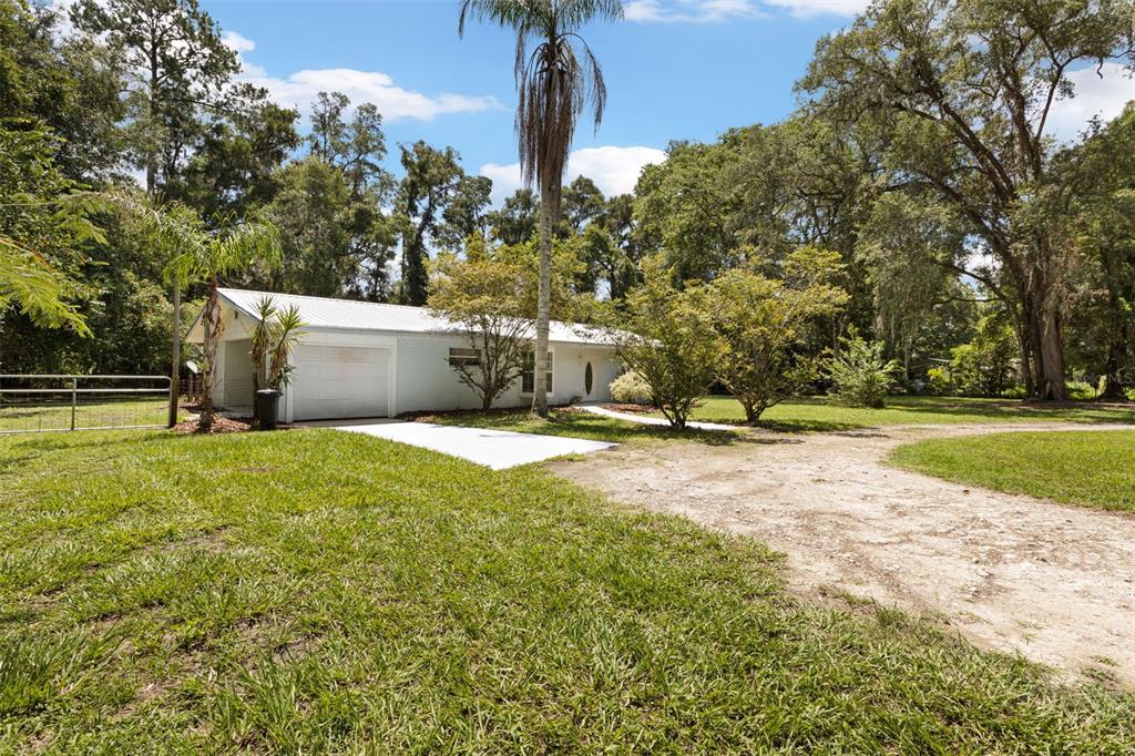 A white single-story house with a metal roof sits on a grassy lot with trees — 3151 NE 176TH TERRACE, WILLISTON, FL