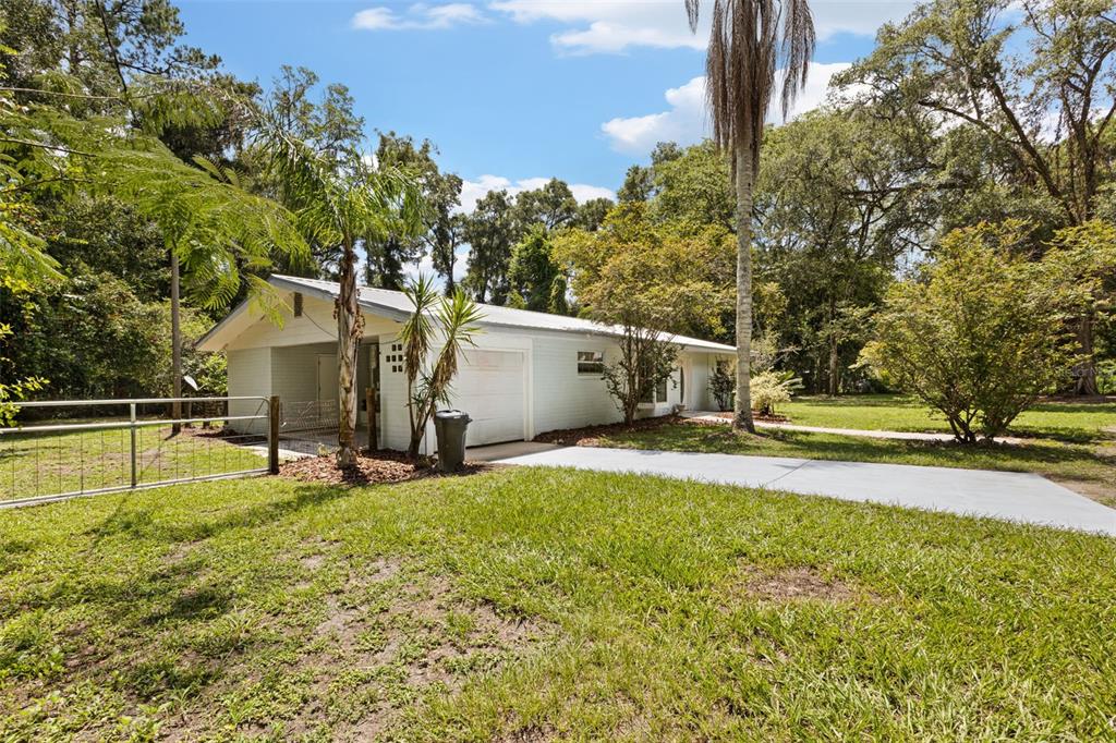 A light-colored, single-story house with a carport and a metal roof sits on a lawn — 3151 NE 176TH TERRACE, WILLISTON, FL