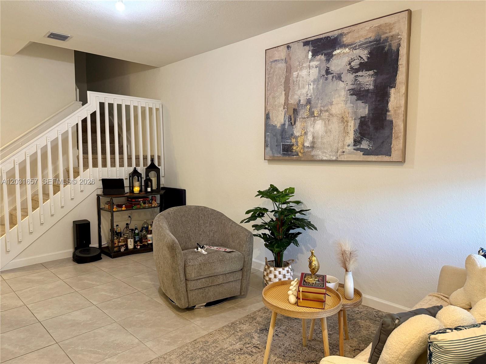 A living room features a gray armchair, a nesting coffee table, and a large abstract painting — 23049 SW 129th Pl, Miami FL 33170, MIAMI, FL