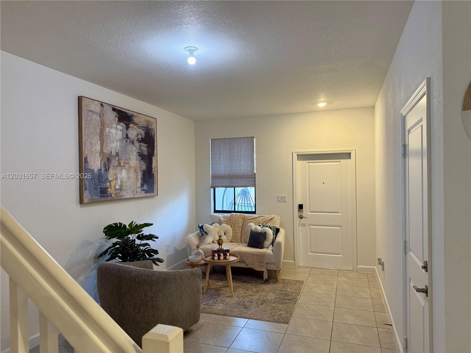 A small living area features a sofa, an armchair, a coffee table, and wall art — 23049 SW 129th Pl, Miami FL 33170, MIAMI, FL