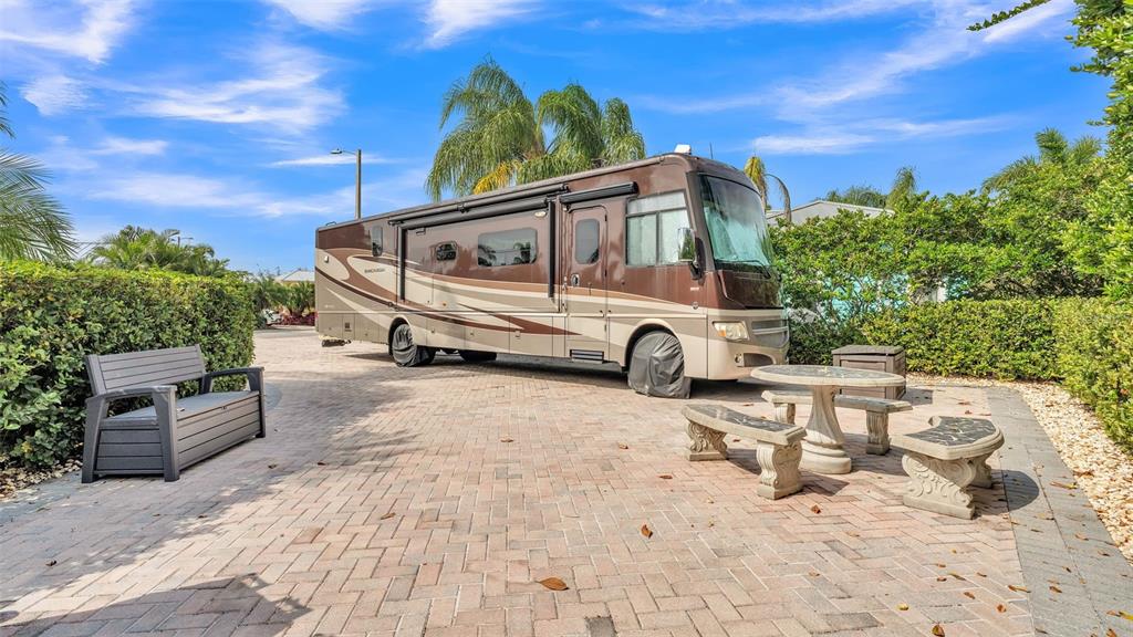 A brown recreational vehicle is parked on a paved patio with outdoor furniture — 3166 GREAT HERON LOOP, POLK CITY, FL