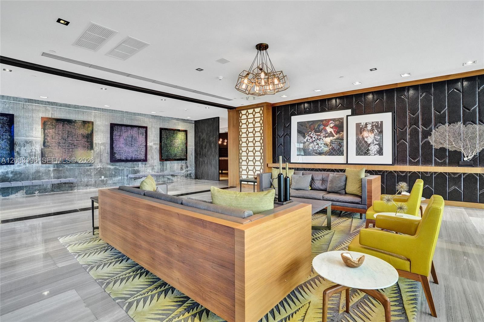 A modern lobby features a wood-framed sofa, yellow armchairs, and abstract art on textured walls — 3470 E Coast Ave # H1205, Miami FL 33137, MIAMI, FL