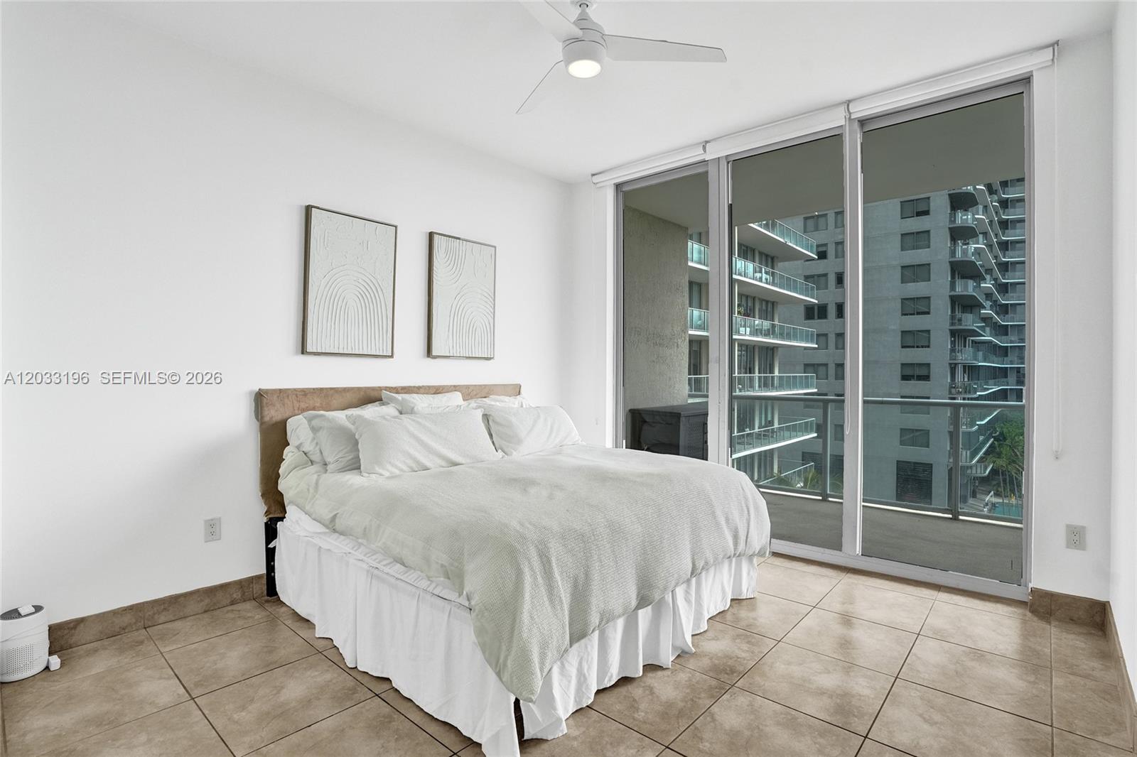 A bedroom features a bed, tile flooring, and a large glass door leading to a balcony — 3470 E Coast Ave # H1205, Miami FL 33137, MIAMI, FL