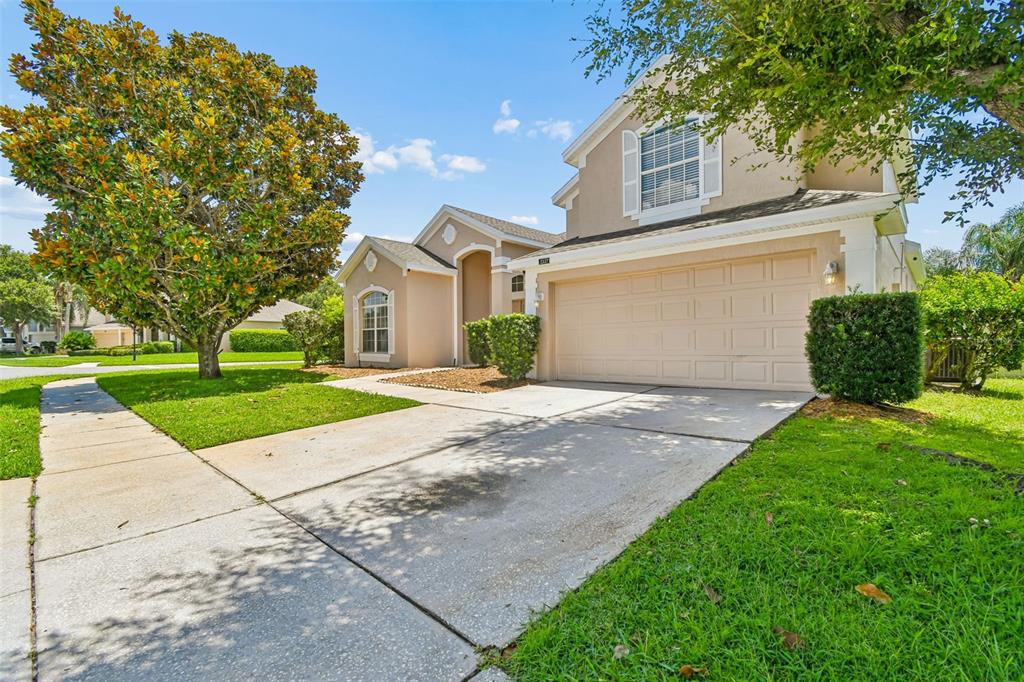 A beige two-story house features a concrete driveway, a two-car garage, and a large tree — 2337 TREYMORE DRIVE, ORLANDO, FL