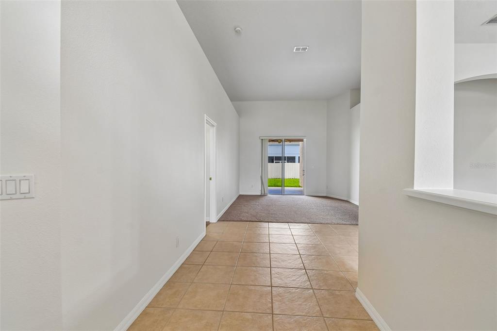 A tiled entryway leads into a carpeted living area with sliding glass doors to the backyard — 2337 TREYMORE DRIVE, ORLANDO, FL