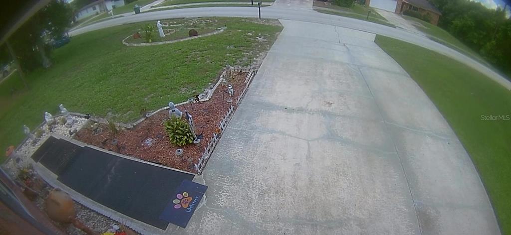 An elevated view shows a concrete driveway, a landscaped garden bed, and a front walkway — 1105 TIVOLI DRIVE, DELTONA, FL
