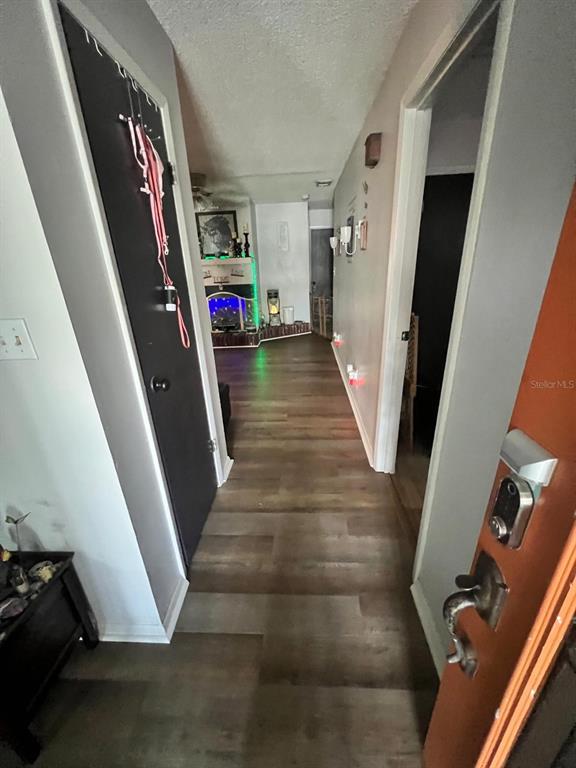 A hallway with wood-look flooring leads from an entryway toward a living area with a fireplace — 1105 TIVOLI DRIVE, DELTONA, FL