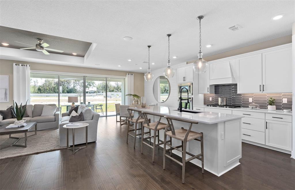A modern open-concept kitchen and living area features white cabinetry, a large island, and flooring — 4990 GOOD DAY LANE, WEST MELBOURNE, FL