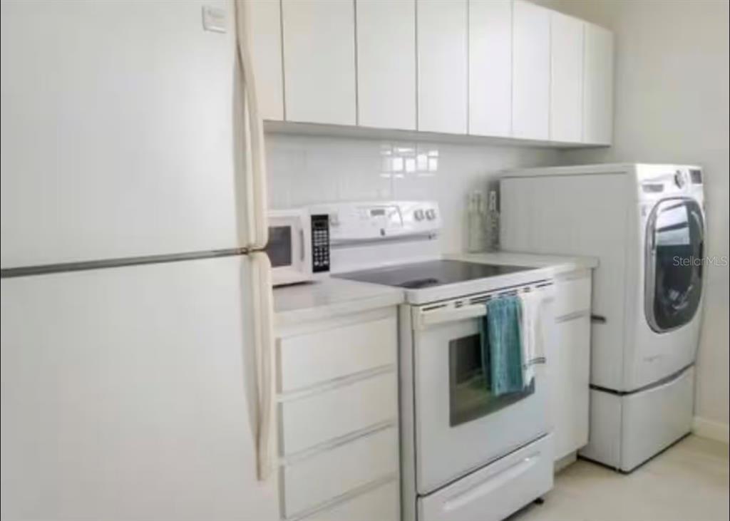 A kitchen featuring white cabinets, white appliances, a stove, and a laundry machine — 1610 PLAYA AZUL, TOWER 3 UNIT 1610, LUQUILLO, PR