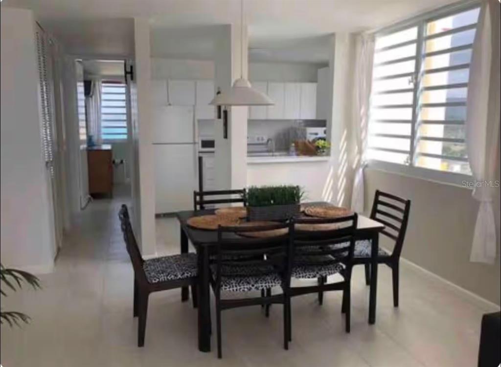 A dining area with a dark table and chairs sits adjacent to a white kitchen — 1610 PLAYA AZUL, TOWER 3 UNIT 1610, LUQUILLO, PR