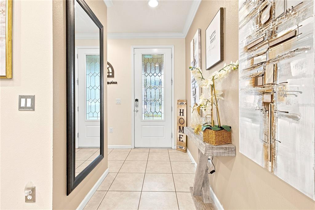 An entryway features a tiled floor, a large mirror, a console table, and a front door — 3821 PINEWOOD GARDENS BOULEVARD, ST CLOUD, FL