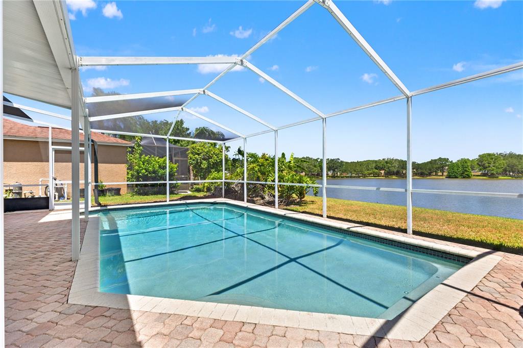 A screened-in swimming pool sits on a brick patio overlooking a lake — 11503 WHISPERING HOLLOW DRIVE, TAMPA, FL