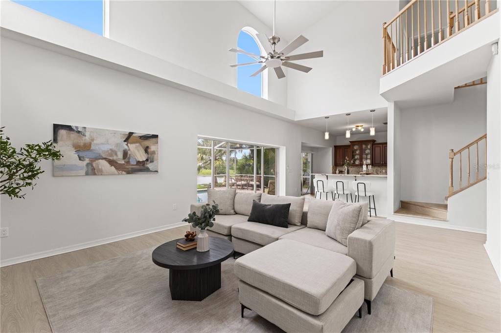 A living room with high ceilings, a sectional sofa, and an open view of a pool — 11503 WHISPERING HOLLOW DRIVE, TAMPA, FL
