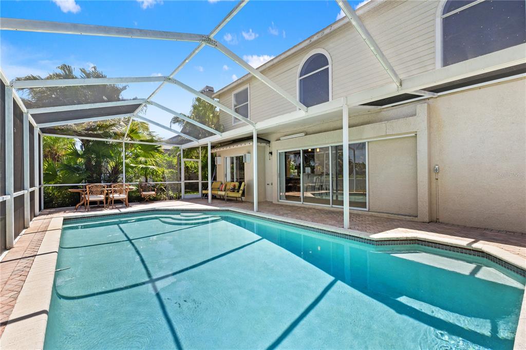 A swimming pool with a screened enclosure sits on a patio next to a house — 11503 WHISPERING HOLLOW DRIVE, TAMPA, FL