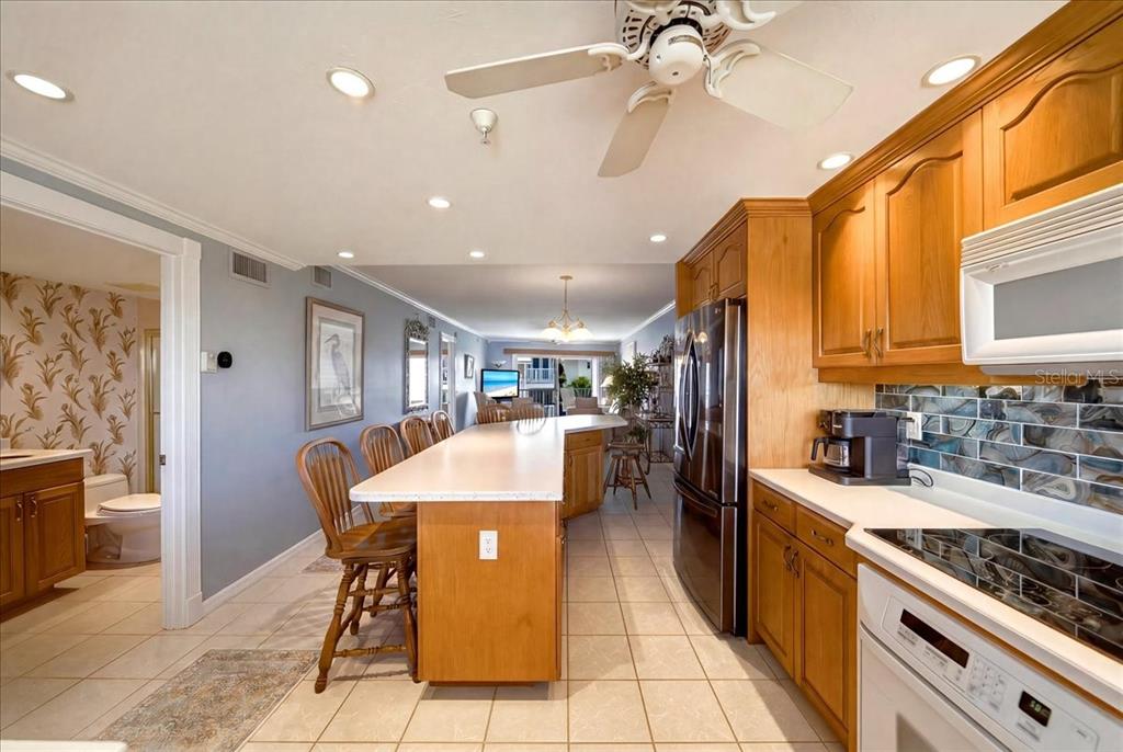 A kitchen with wood cabinets, a long island with bar seating, and tile flooring — 1480 GULF BOULEVARD UNIT 202, ENGLEWOOD, FL