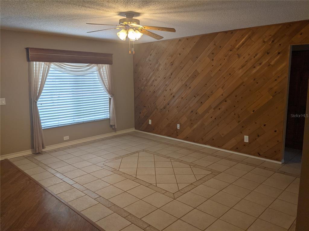 A room with diagonal wood-paneled walls, tiled flooring, and a ceiling fan — 333 BRANDYWINE DRIVE, VALRICO, FL