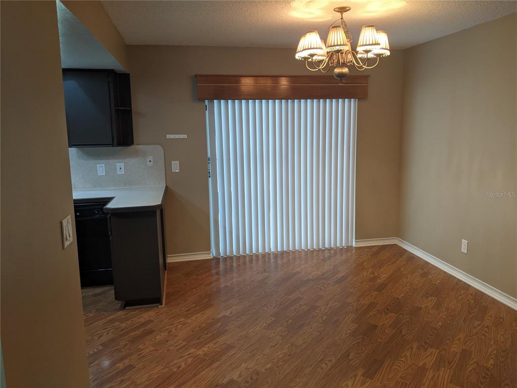 A dining area features wood-look flooring, a chandelier, and a sliding glass door with blinds — 333 BRANDYWINE DRIVE, VALRICO, FL