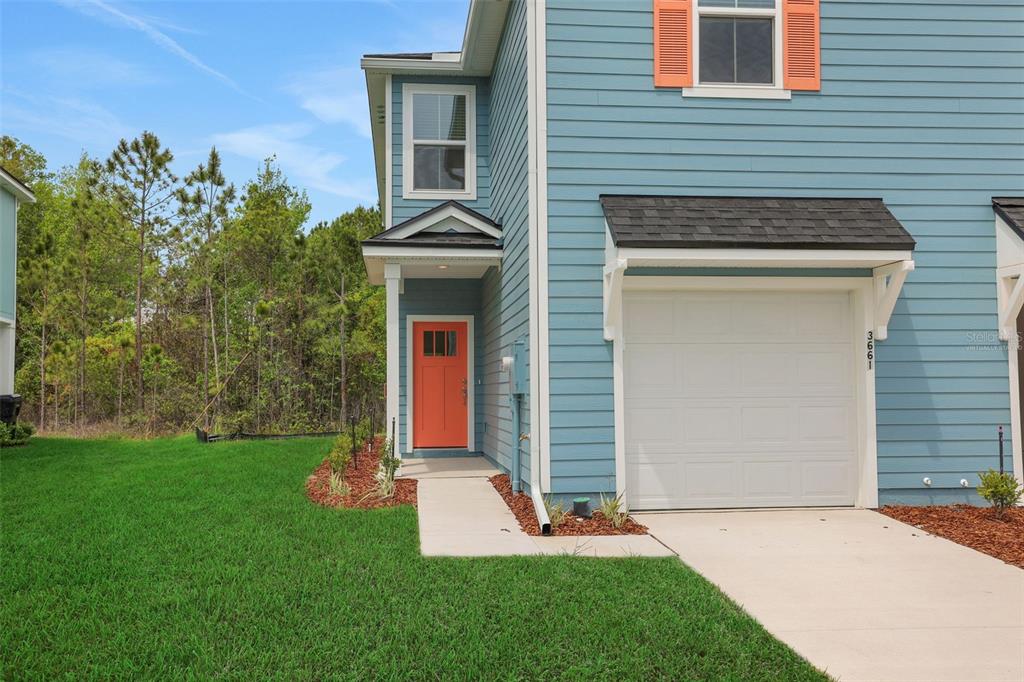 A blue two-story townhouse features an orange front door, a single-car garage, and a lawn — 3717 ATHENIAN WAY, MIDDLEBURG, FL