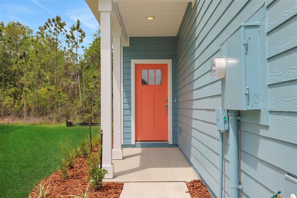 A bright orange front door is set against light blue siding on a covered porch — 3717 ATHENIAN WAY, MIDDLEBURG, FL