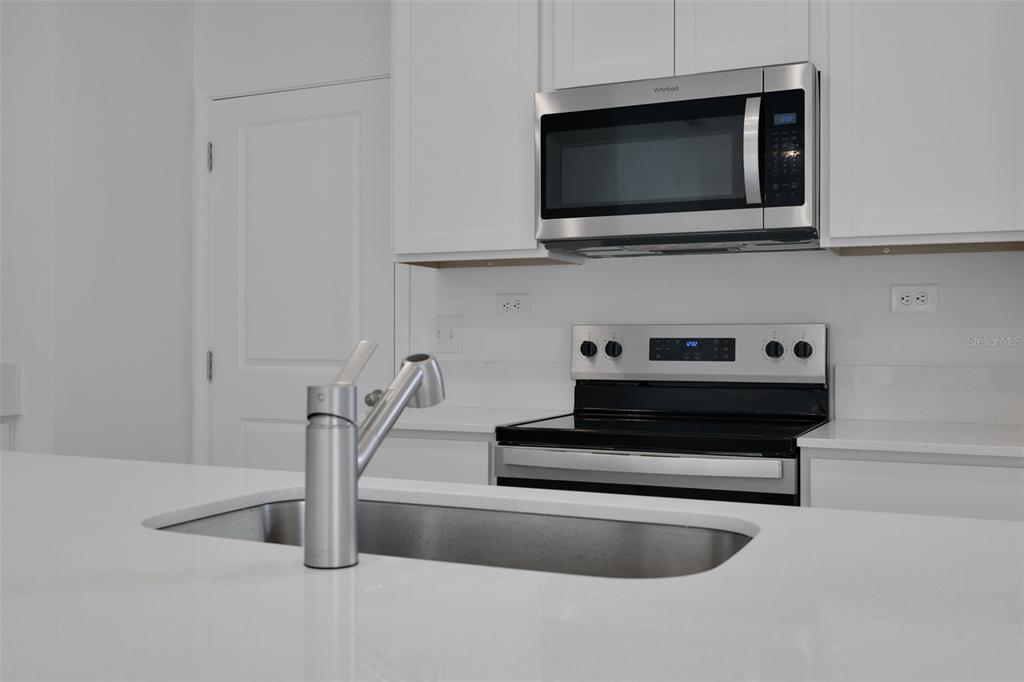 A kitchen features white cabinets, stainless steel appliances, and a white quartz island countertop — 3717 ATHENIAN WAY, MIDDLEBURG, FL