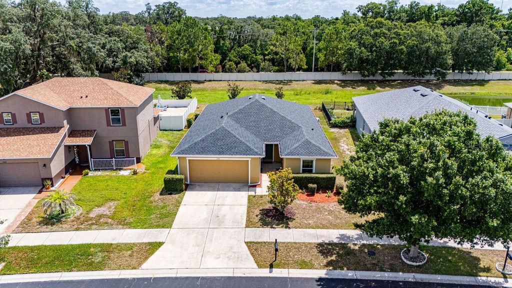 An aerial view shows three suburban houses with driveways and lawns near a wooded area — 11018 RUNNING PINE DRIVE, RIVERVIEW, FL