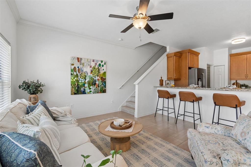 A living room with a sofa, coffee table, and stairs leading to an open kitchen — 10820 CELTIC WOODS AVENUE, TAMPA, FL