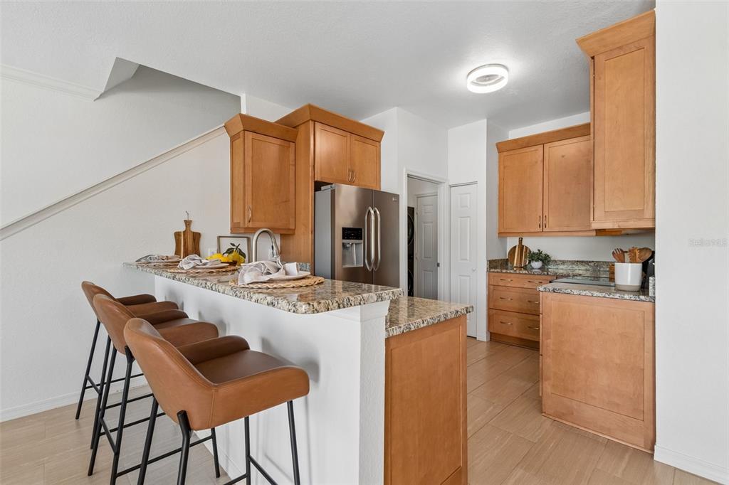 A kitchen with light wood cabinets, granite countertops, stainless steel appliances, and a breakfast bar — 10820 CELTIC WOODS AVENUE, TAMPA, FL