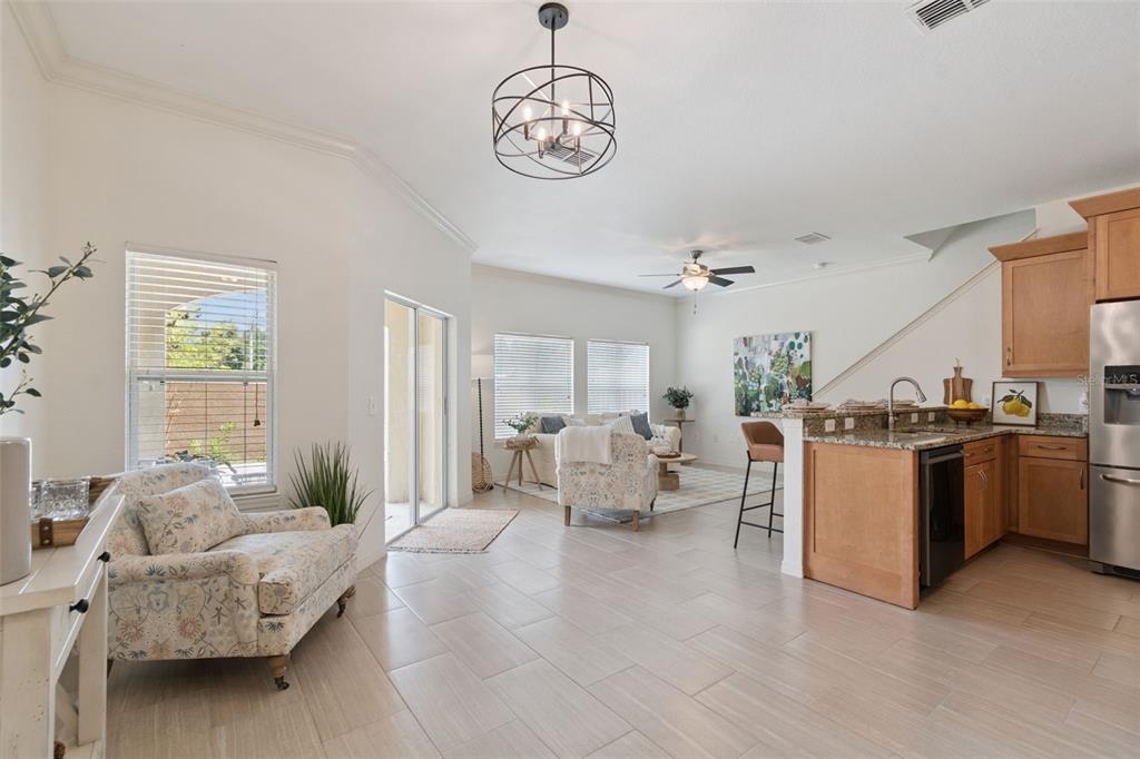 An open-concept living area features tile flooring, a kitchen island, and a dining light fixture — 10820 CELTIC WOODS AVENUE, TAMPA, FL