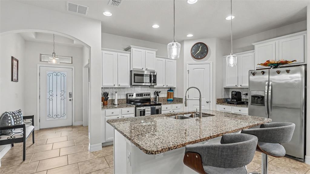 A kitchen features white cabinets, granite countertops, a center island, and stainless steel appliances — 4007 PRIMA LAGO CIRCLE, LAKELAND, FL