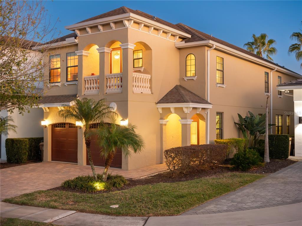 A two-story stucco house with a two-car garage, arched balcony, and a paved driveway — 7816 LOXAHATCHEE COURT, REUNION, FL
