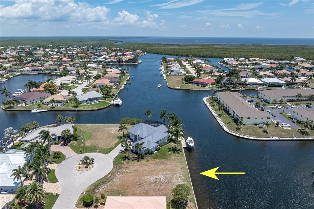An aerial view shows a waterfront residential lot with a seawall and a nearby house — 1474 KITTIWAKE DRIVE, PUNTA GORDA, FL