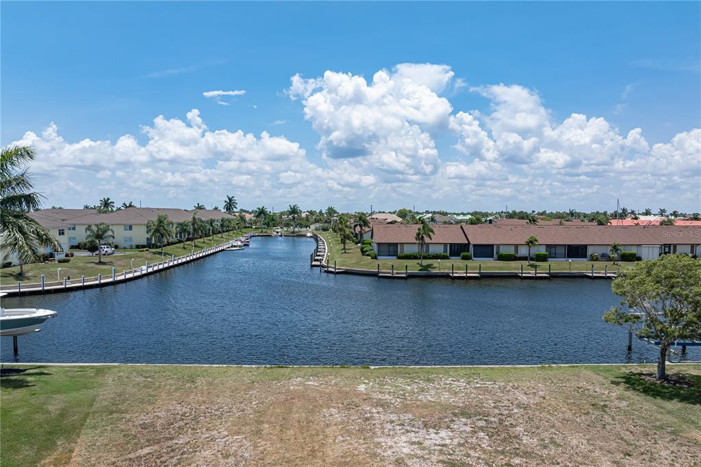 A view of a canal lined with residential buildings and boat docks under a blue sky — 1474 KITTIWAKE DRIVE, PUNTA GORDA, FL