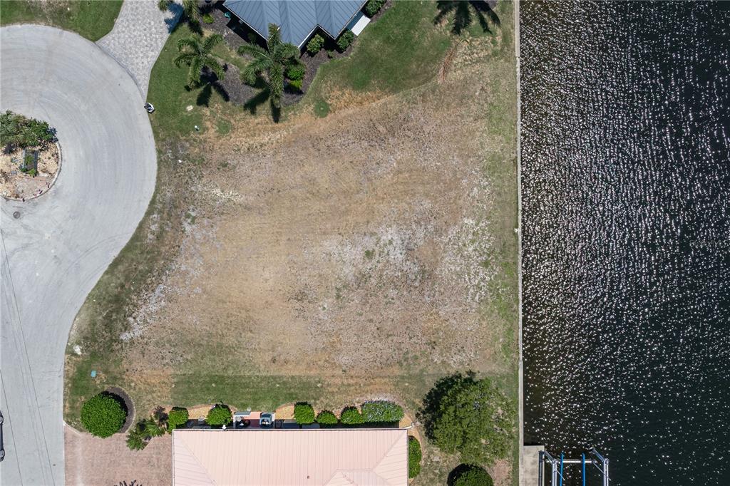 An aerial view shows a vacant waterfront lot situated between two existing residential properties — 1474 KITTIWAKE DRIVE, PUNTA GORDA, FL