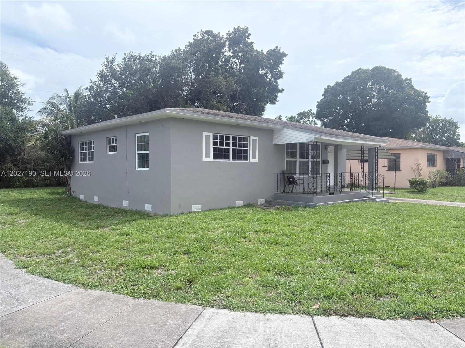 A single-story gray house with a front porch and white-trimmed windows sits on a lawn — 1100 NW 110th St, Miami FL 33168, MIAMI, FL