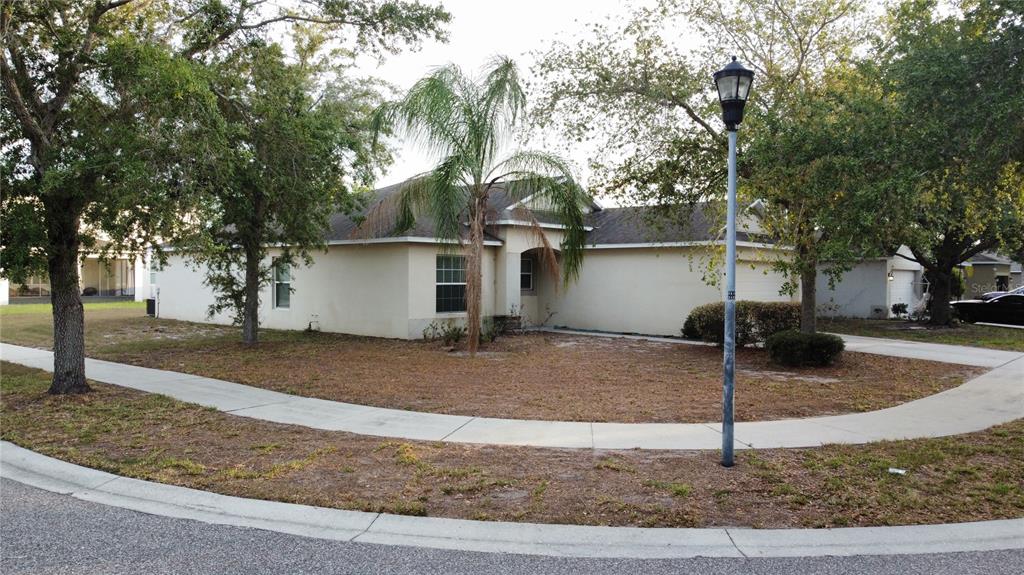 A single-story house with a beige exterior, a palm tree, and a sidewalk in front — 7538 TURTLE VIEW DRIVE, SUN CITY CENTER, FL
