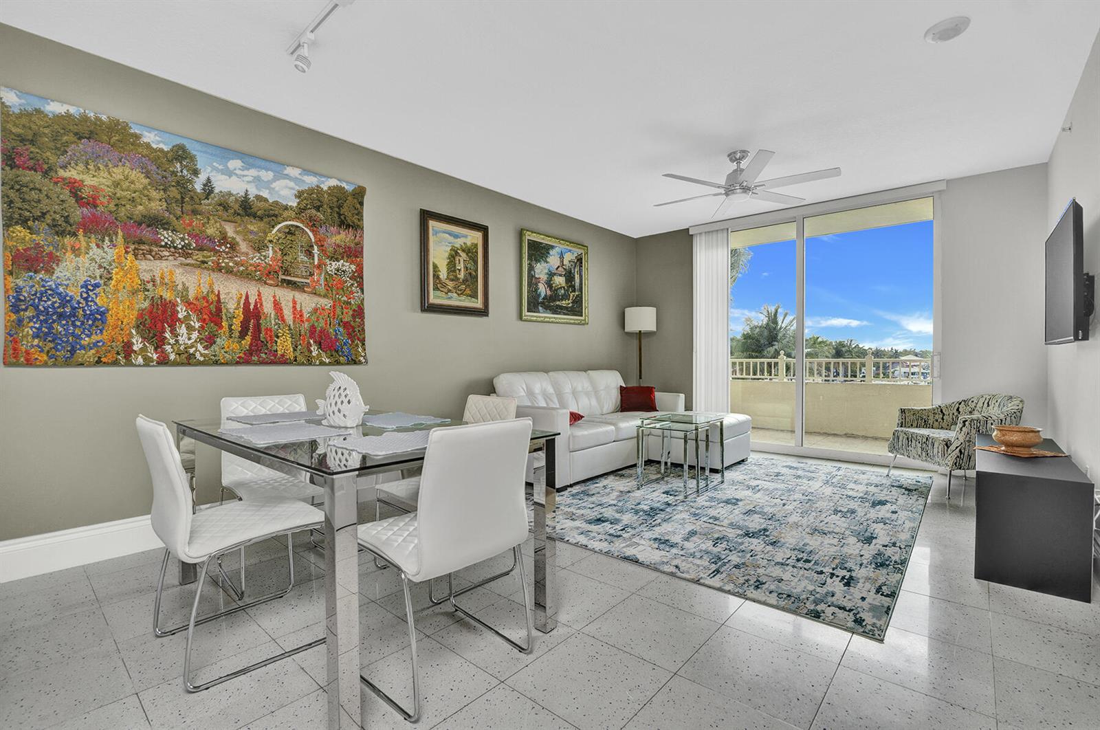 A living and dining area features white furniture, a patterned rug, and a balcony view — 100 NE 6th Street # 203, Boynton Beach FL 33435, BOYNTON BEACH, FL