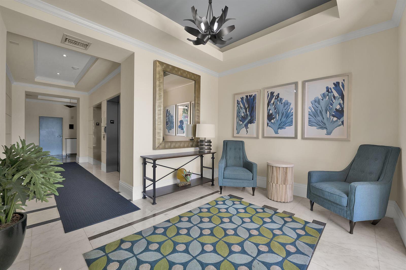 A lobby area features two blue armchairs, a console table, a mirror, and patterned rug — 100 NE 6th Street # 203, Boynton Beach FL 33435, BOYNTON BEACH, FL