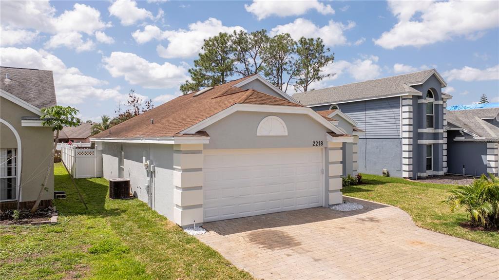 A light gray house with a white garage door and a brown shingled roof — 2218 NEWT STREET, ORLANDO, FL