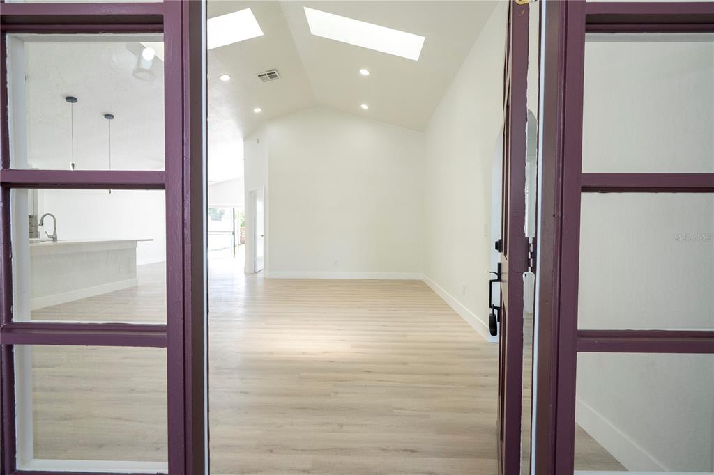 A view through double glass doors into a bright room with vaulted ceilings and skylights — 2218 NEWT STREET, ORLANDO, FL