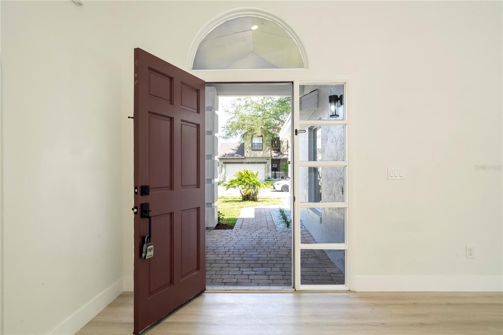 An open front door reveals a brick walkway and a view of a neighboring house — 2218 NEWT STREET, ORLANDO, FL