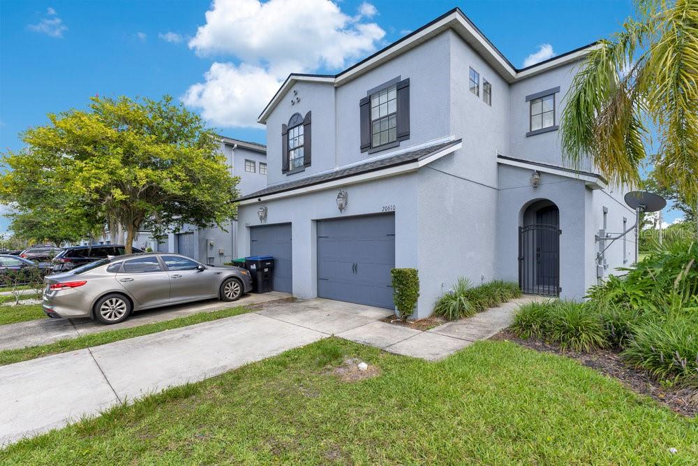 A two-story gray stucco townhouse with a two-car garage and a paved driveway — 20610 MAXIM PARKWAY, ORLANDO, FL