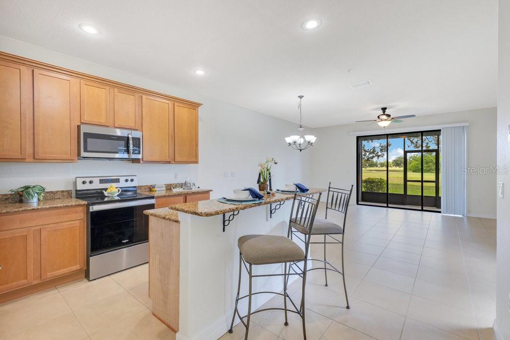 A kitchen with wood cabinets and granite countertops overlooks a dining area and sliding doors — 20610 MAXIM PARKWAY, ORLANDO, FL