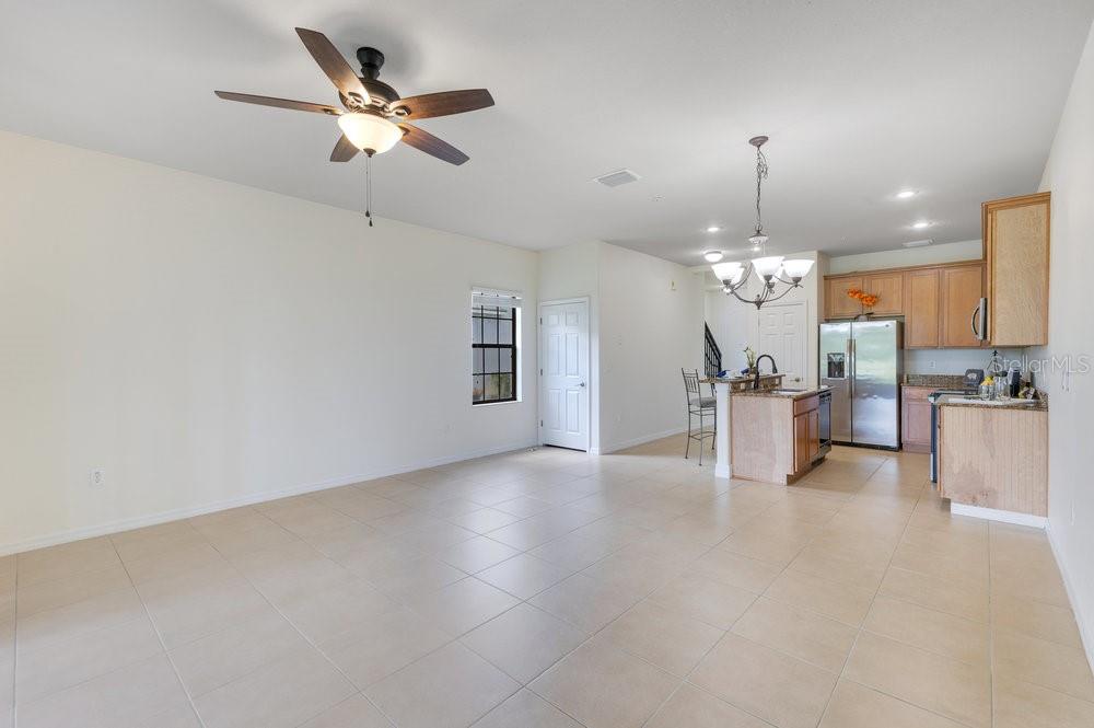 An open-concept living area features tile flooring, a ceiling fan, and an adjacent kitchen — 20610 MAXIM PARKWAY, ORLANDO, FL