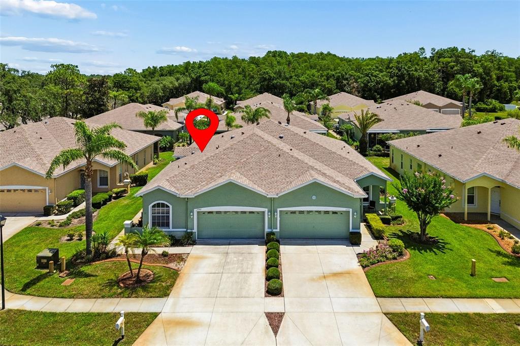 An aerial view of a green duplex home with a two-car garage and shingled roof — 12200 PUTTER GREEN COURT, NEW PORT RICHEY, FL