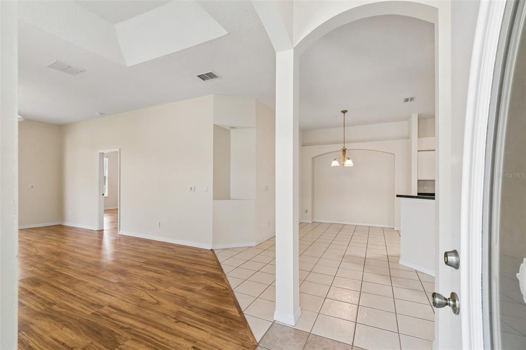 An interior view shows a living room with wood flooring and an adjacent tiled dining area — 12200 PUTTER GREEN COURT, NEW PORT RICHEY, FL