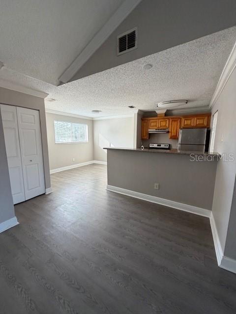 An open-concept kitchen with wood cabinets and a breakfast bar overlooks a living area — 7298 ULMERTON RD UNIT 611, LARGO, FL